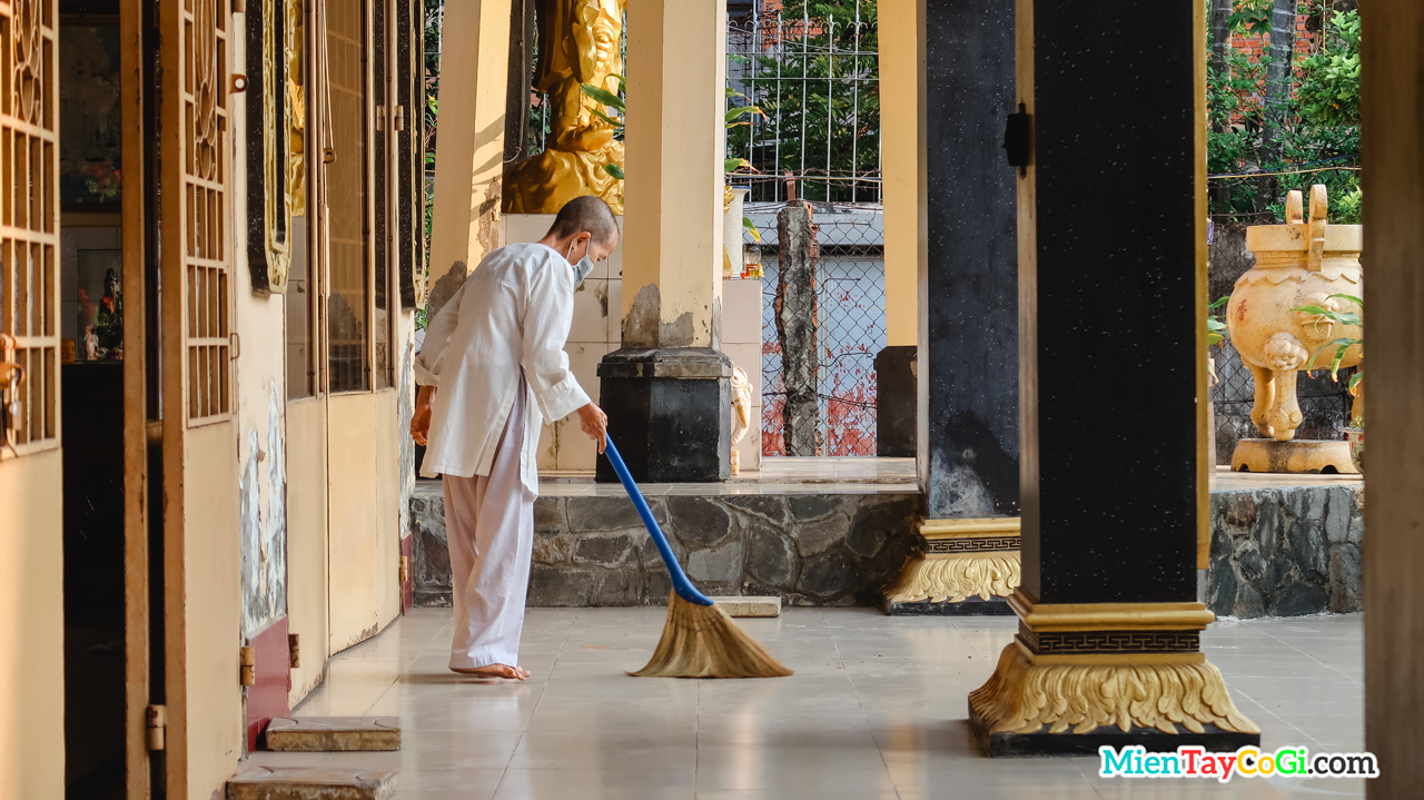 Một sư cô đang quét dọn vệ sinh chùa