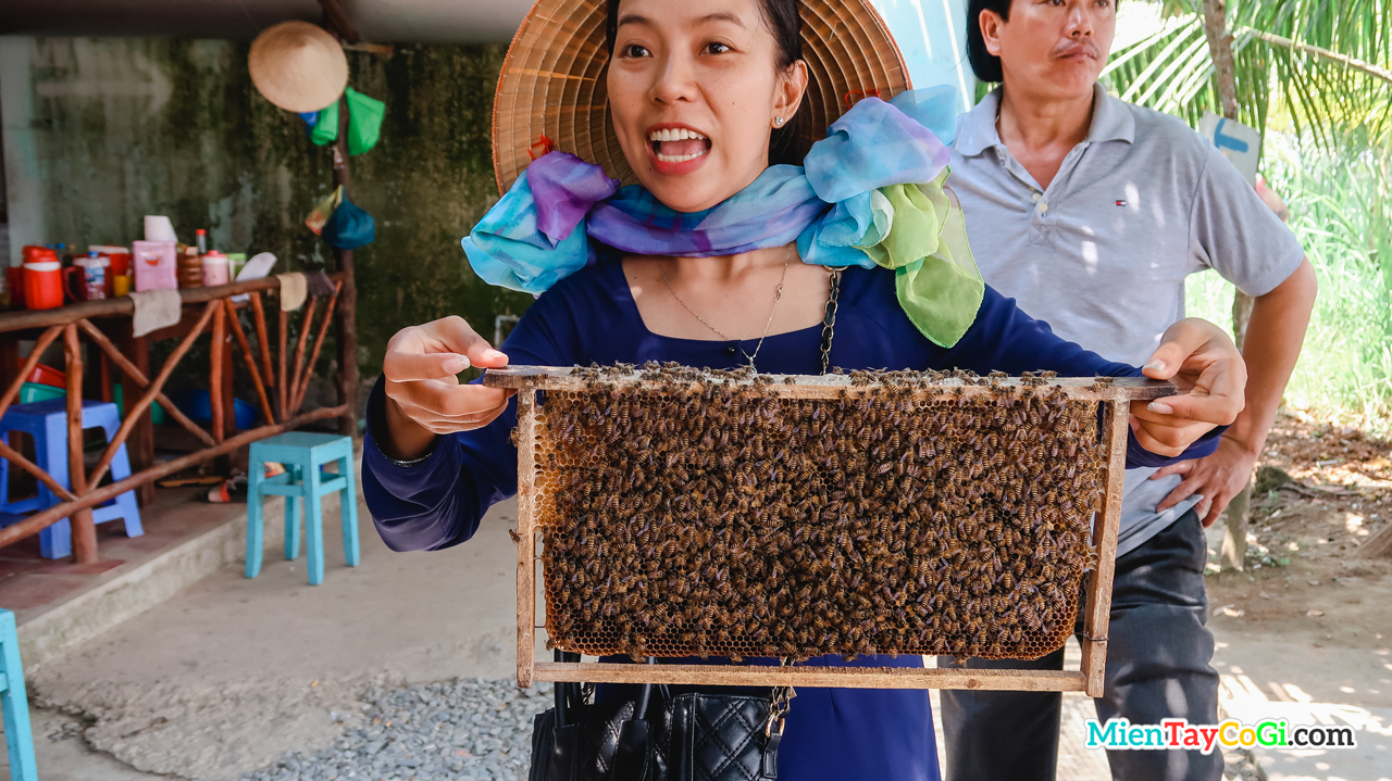 The tour guide happily modeled how to hold a honeycomb